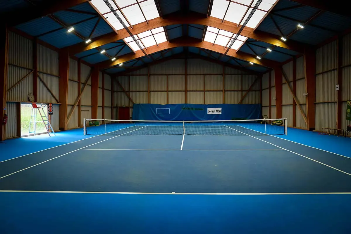 Le court de tennis couvert du club, surface green set bleue, vu depuis le fond de court